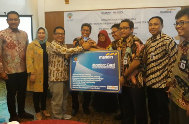 SINERGI : Area Head Semarang PT Bank Mandiri Opa Supandi ( tiga dari kiri) dan Direktur Utama Perusda CMJT Agung Rochmadi secara simbolis menunjukkan replika kartu sejuta manfaat. ( foto : dekan bawono/ jateng pos)