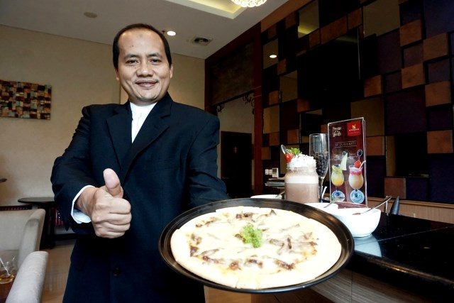 MENU SPESIAL : Muhamad Noor Cholis GM Noorman Hotel Semarang tengah menunjukan menu baru Pizza Rendang. Foto : PRAST WD/JATENG POS.