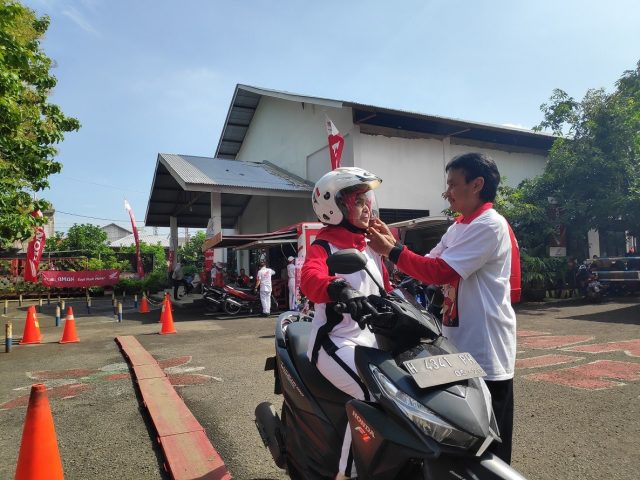 KAMPUNG SAFETY : Lurah Pandean Lamper, Mohamad Tavip memperagakan penggunaan helm yang benar dan aman kepada istrinya, yaitu sampai terdengar bunyi klik di pengait helm. FOTO: Istimewa for jateng pos. (