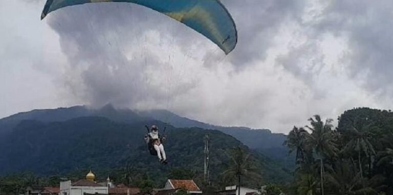 LANDING: Aksi salah satu peserta Festival Paralayang 2025 mengenakan kostum tokoh pewayangan Anoman saat akan landing di lapangan Desa Rowoboni, Banyubiru, Minggu (20/4/2025). FOTO: MUIZ/JATENGPOS